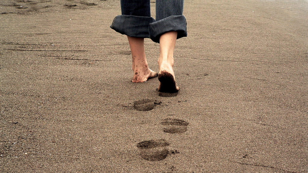 person walking on beach, a symbol of following Jesus