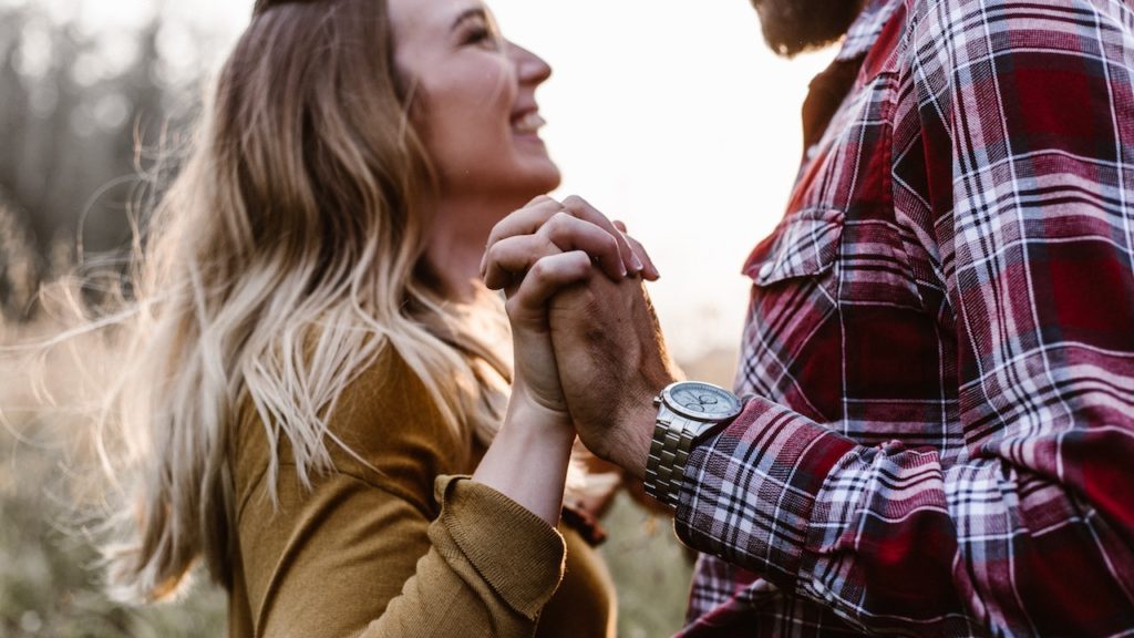 couple holding hands, smiling at each other
