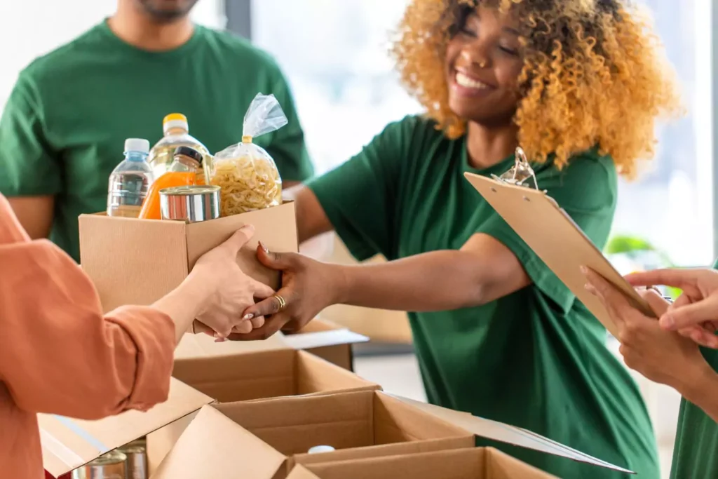a woman handing out a box of food at a local ministry