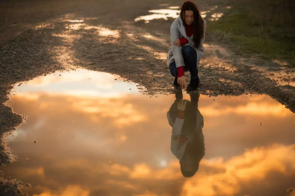 a woman looking at her reflection in a pond, a symbol of her sexuality