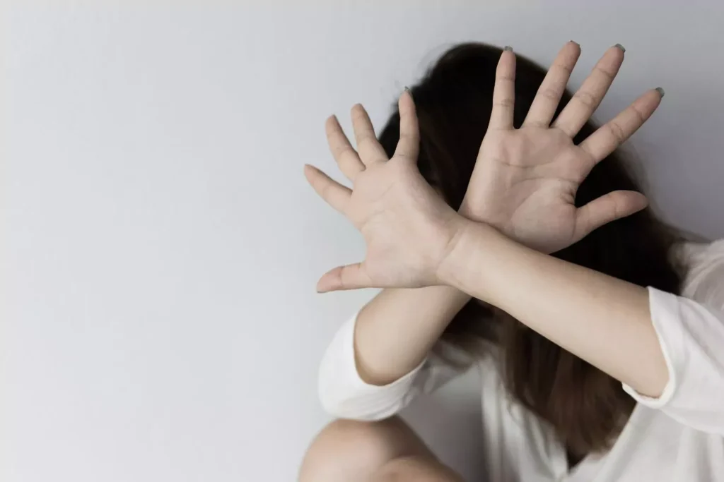 a woman with her hands up blocking her face from domestic violence