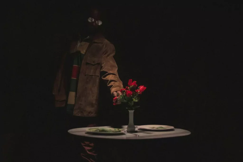 a man touching a vase of flowers on a set table, wishing he was on a date