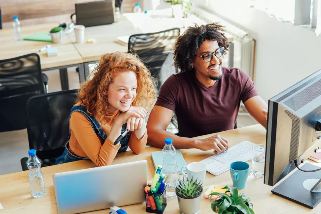 a male and female co-worker, working together at their computers