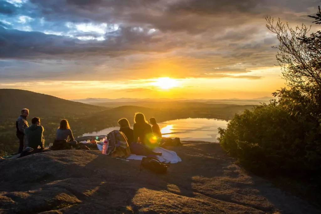 people sitting on a cliff side, watching the sun set, craving connection