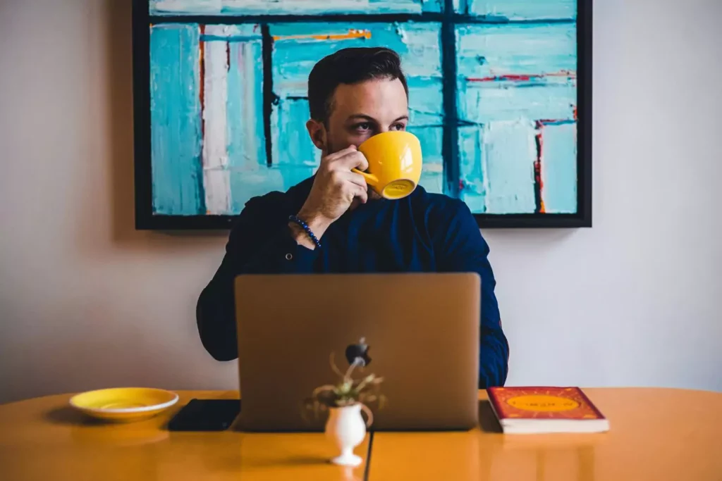 a man drinking coffee at his computer trying to get out of unemployment