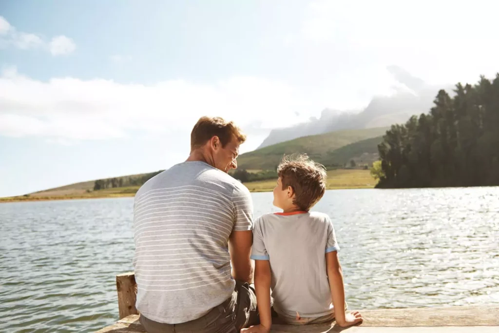a father and son sitting on a dock
