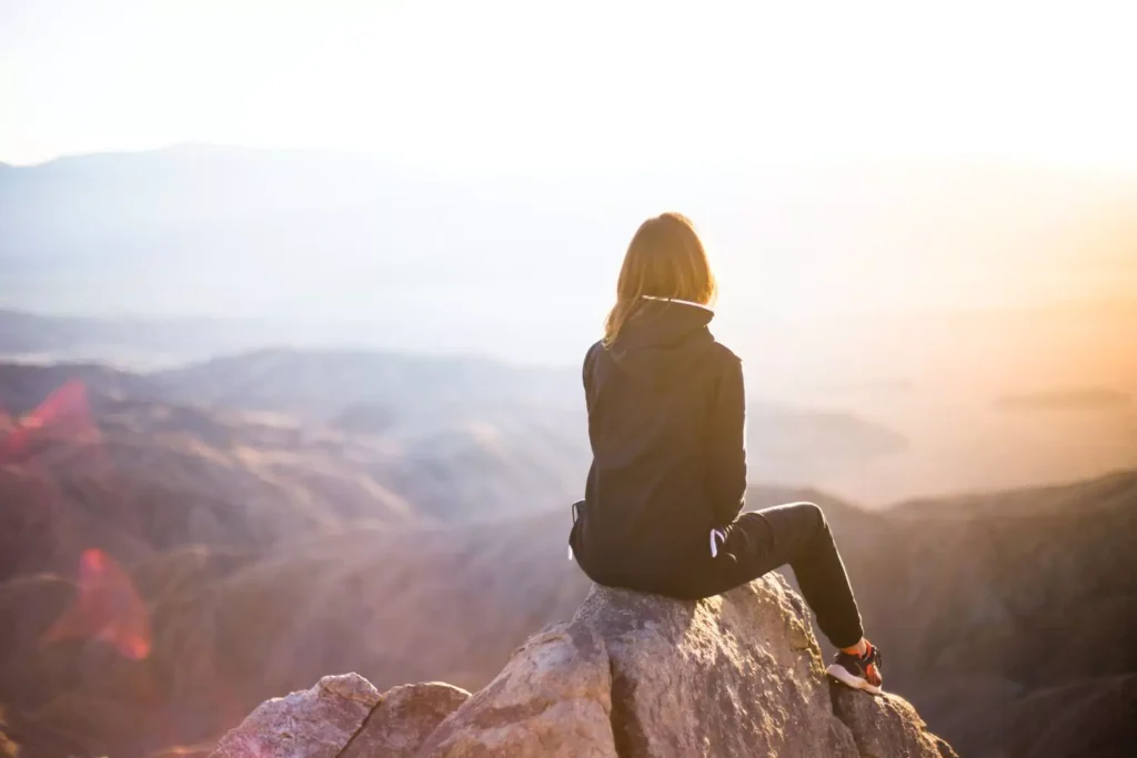 a woman sitting alone on a mountain, giving God control of her singleness
