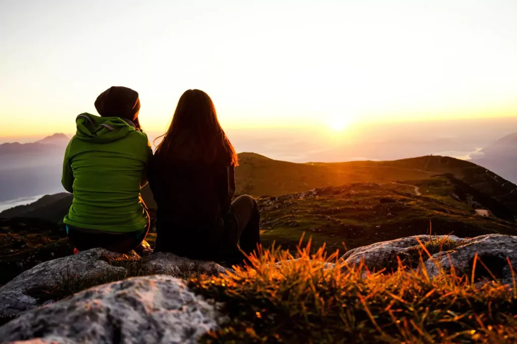 two women sitting on a mountain sharing stories of their lives with one another