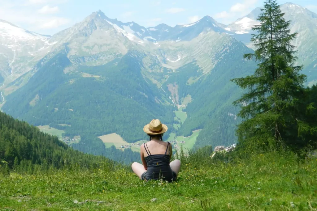 a woman sitting in the grass, looking at mountains, making the most of her unemployment