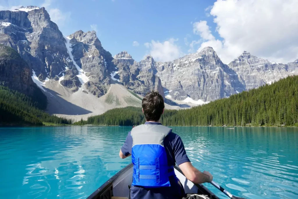 a man enjoying a time of leisure, canoeing on a mountain lake