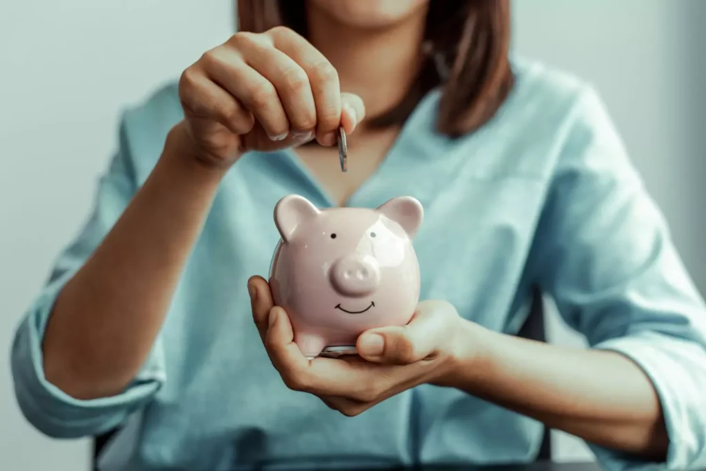 a woman getting money ready by putting a coin into her piggy bank