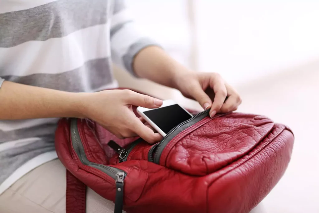 a woman putting her phone in her backpack; she's doing a tech fast