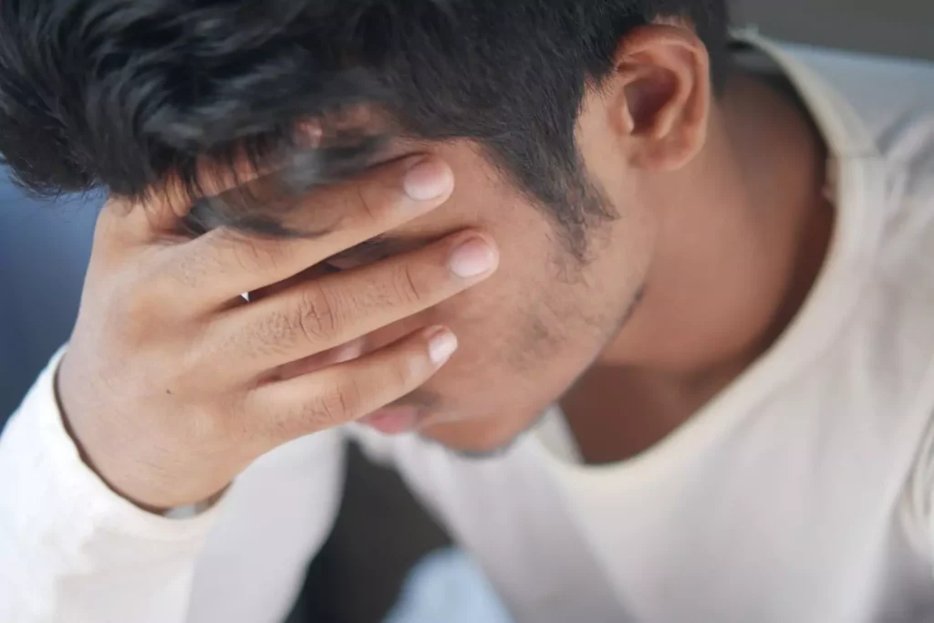 a man with his hand on his forehead, feeling shame