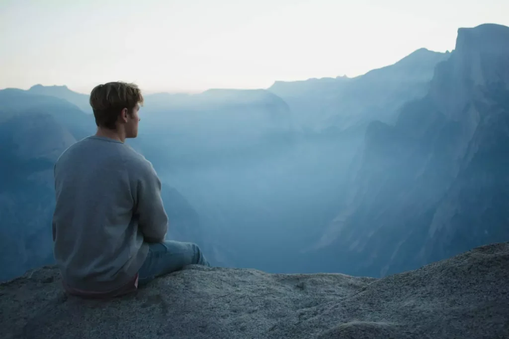 a worried man sitting on a mountain