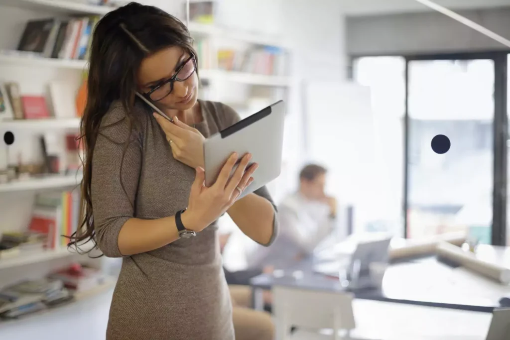 a woman multitasking by talking on the phone and reading her iPad at the same time
