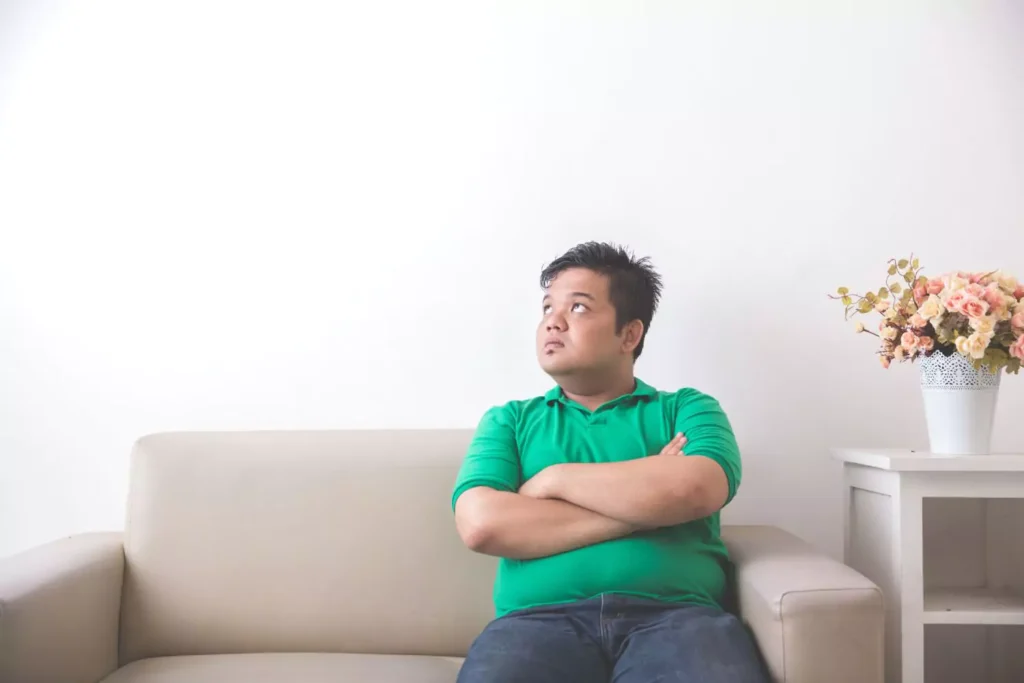 a man struggling with his weight sitting on a couch
