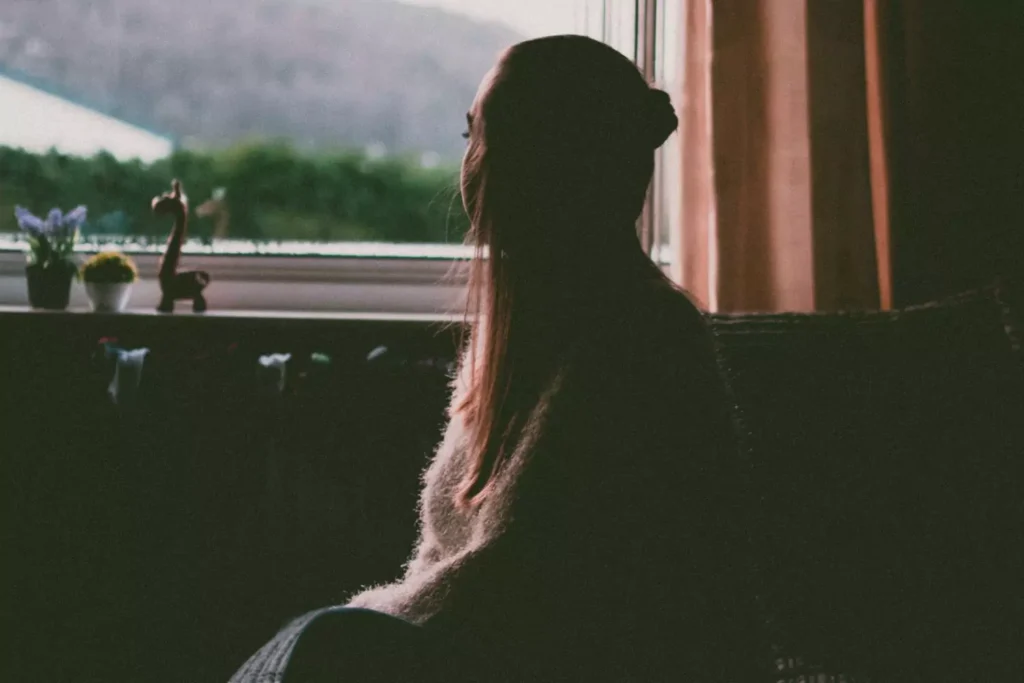 a girl looking out a window, considering her sin