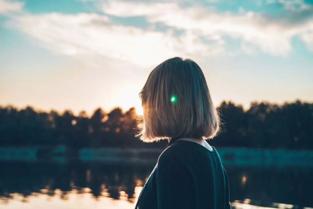 a woman looking out over a lake thinking who can you trust?